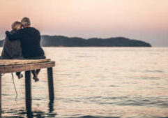 Loving senior couple enjoying the sunset, sitting on the dock